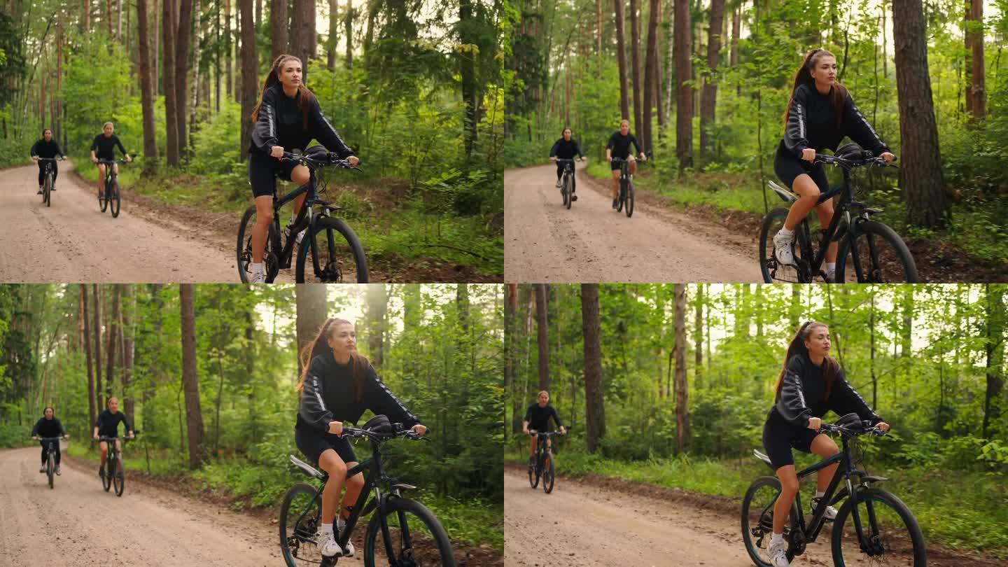 三个年轻的成年妇女骑自行车在自然公园在阳光明媚的早晨，运动和娱乐
