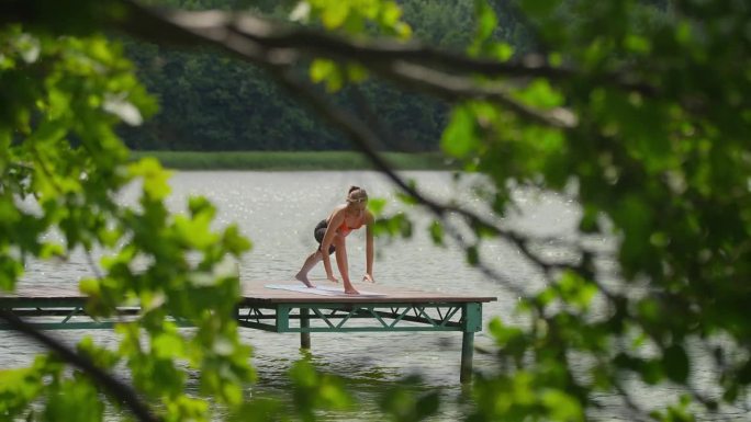 在湖边运动的女人。躺在木栈桥上，欣赏美丽的景色
