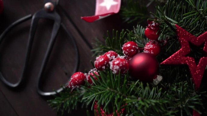 圣诞花环制作与自己的手的节日视频。房子的装饰和装饰，冷杉树枝，星星，球果，电线和剪刀躺在桌子上，从上