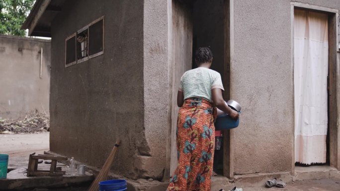 一名妇女拿着干净的餐具。母亲进屋时，女孩站在门口。小屋的外观。纪录片镜头