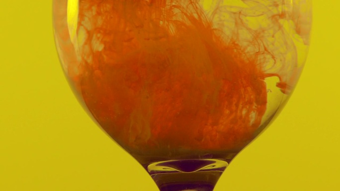 玻璃中的橙色液体与水形成云
