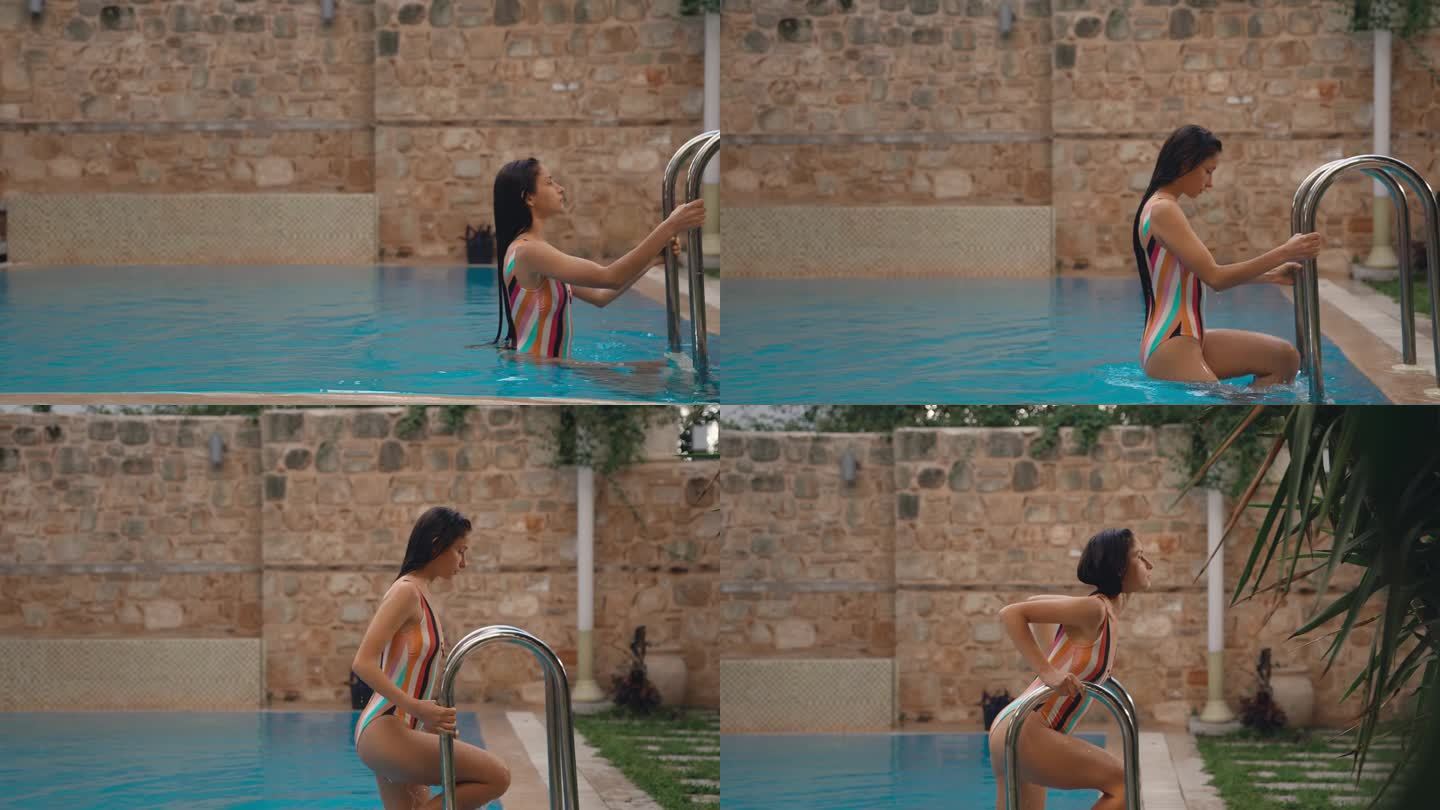 一个年轻的长发女子，穿着泳装，身材优美，从泳池里出来的慢动作很性感。水滴顺着女孩的身体流下来。