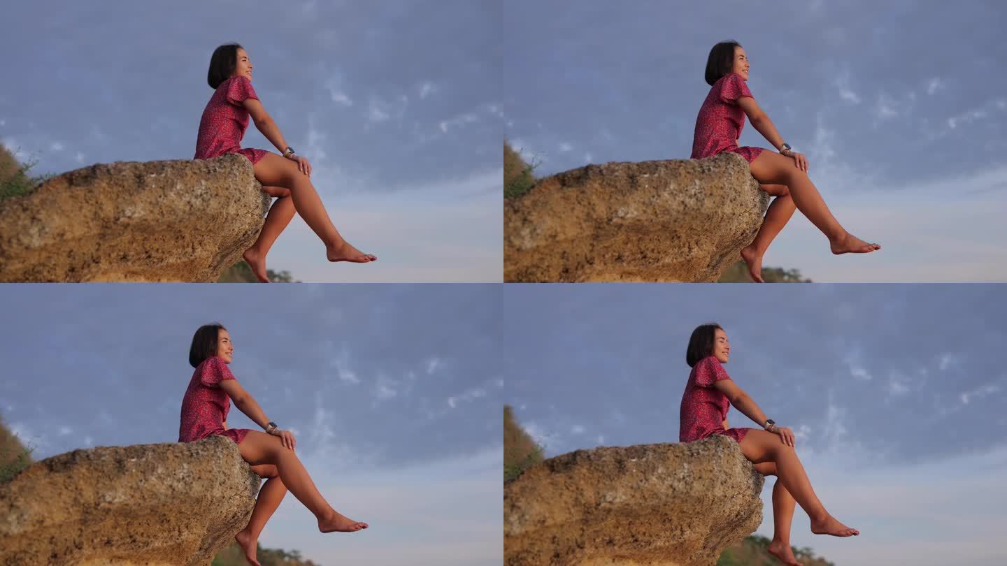 一个快乐的女人坐在一块石头上，背景是天空