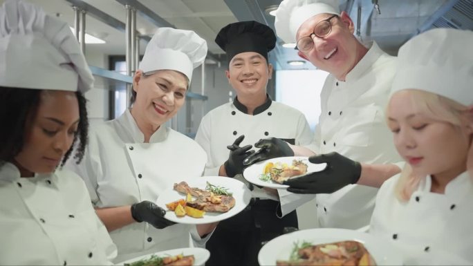 一群身穿白色制服、头戴帽子的专业男女厨师，在厨房里展示着烹制后的一盘肋眼牛排，脸上带着微笑和幸福。