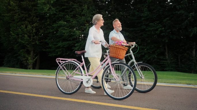 两口老人在户外骑着自行车散步