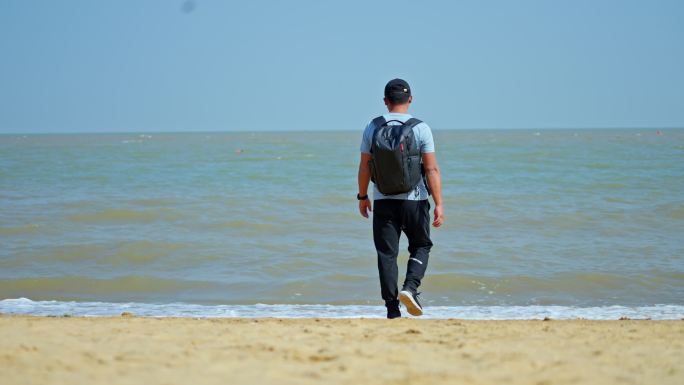 一个背包男人向海边走去背影