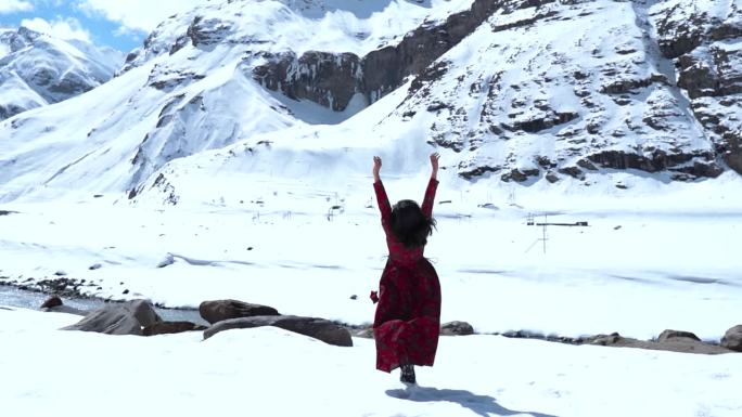 一个十几岁的印度女孩在印度拉胡尔的雪山前举手的慢动作镜头。在寒冷晴朗的日子里，山里的女孩。