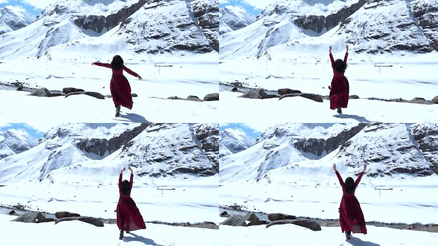 一个十几岁的印度女孩在印度拉胡尔的雪山前举手的慢动作镜头。在寒冷晴朗的日子里，山里的女孩。