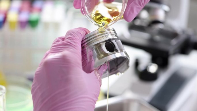 在实验室的特写镜头中，科研人员将发动机油倒在汽车活塞上