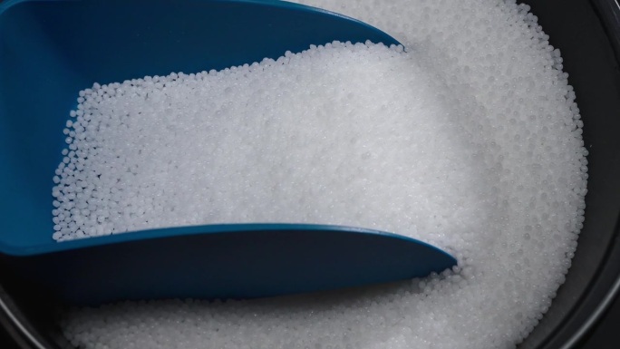 用勺子检查生产中聚合物复合材料的质量。白色塑料颗粒装在一个特殊的容器里。生产工艺