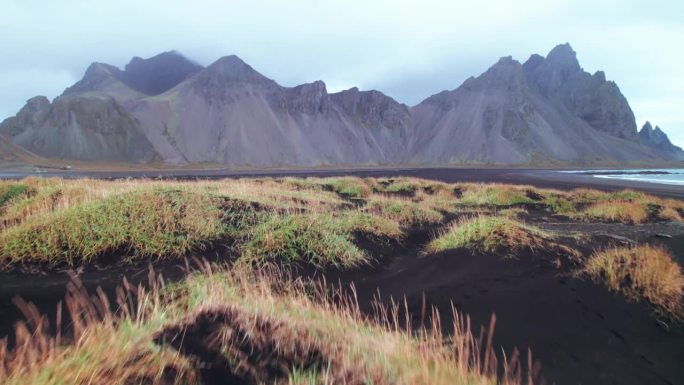 航拍:黑沙滩、tussocks和Vestrahorn的仰角图，其标志性的锯齿状山峰和高耸的扶壁，从这