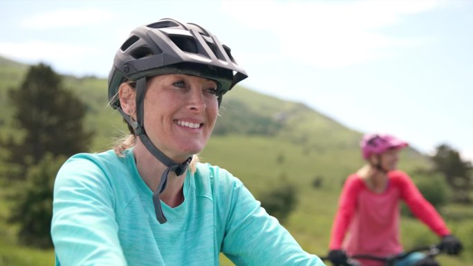 美丽的女山地自行车手坐在她的电动自行车和微笑