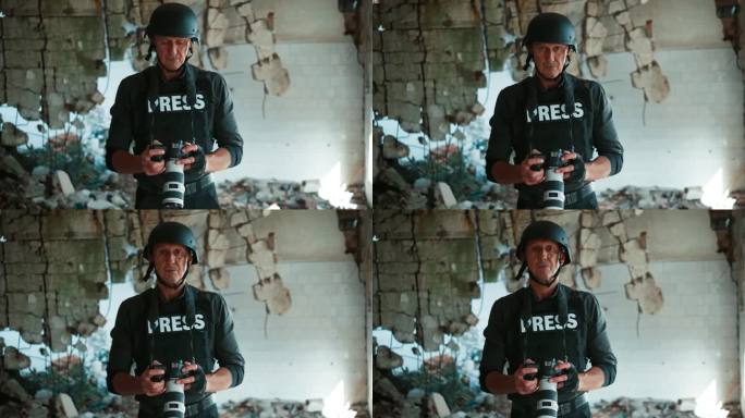 一个成熟的男人戴着头盔，穿着防弹背心，在战区拍照，拿着数码相机，看着相机
