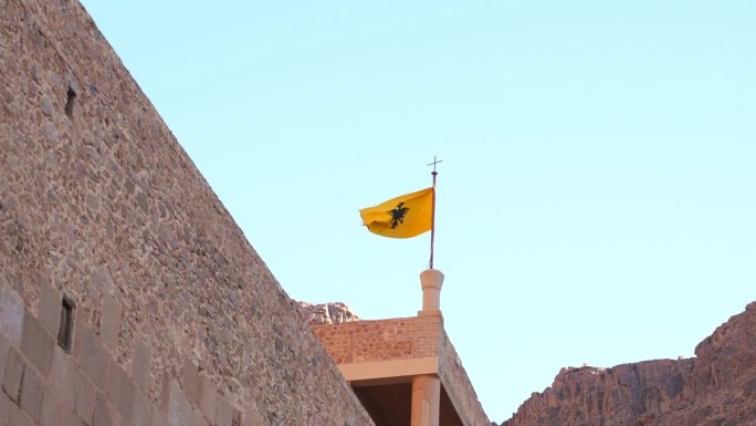 圣凯瑟琳修道院屋顶上的拜占庭帝国双头鹰旗的变焦镜头。西奈山的古代历史宗教场所。游览摩西山