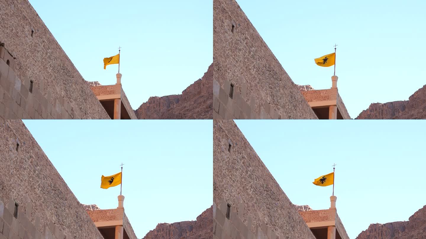 圣凯瑟琳修道院屋顶上的拜占庭帝国双头鹰旗的变焦镜头。西奈山的古代历史宗教场所。游览摩西山