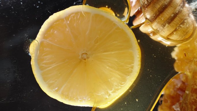 从下面透过玻璃桌子看柠檬片，蜂蜜从上面滴下来。特写镜头。