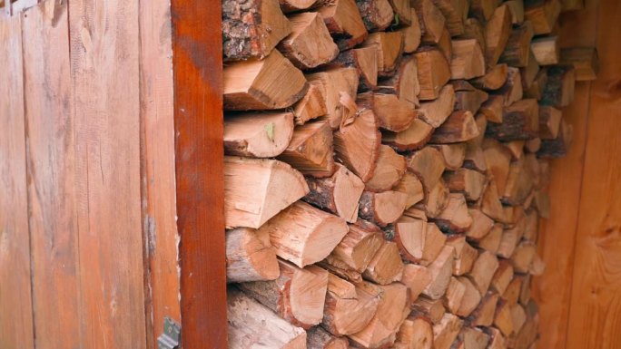 小木屋的柴火棚内完全堆满了橡木柴火，镜头移动流畅。资源储存用于冬季采暖季节，固体燃料采暖