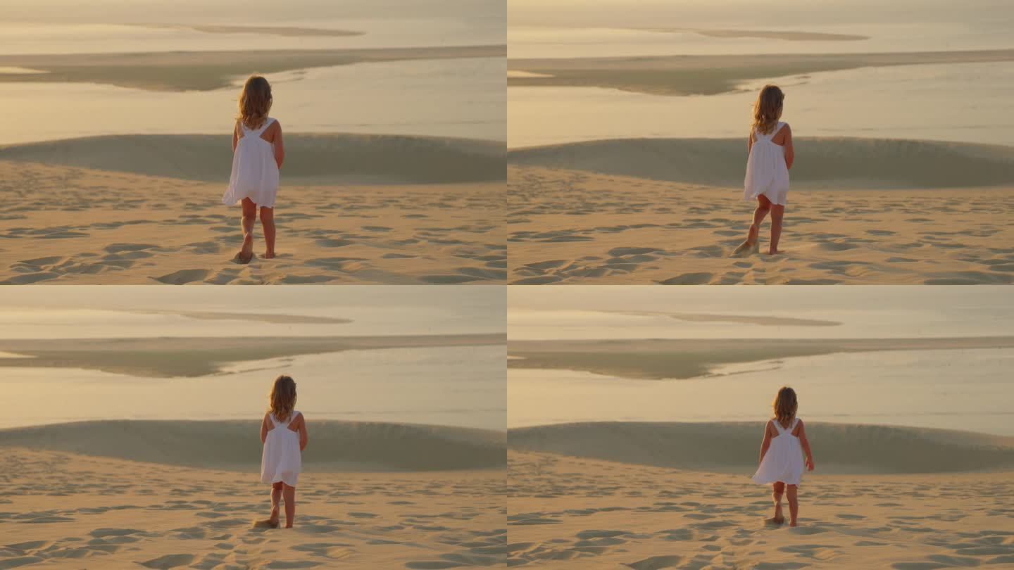 一个美丽的小女孩，穿着白色的裙子，赤脚走在沙滩上，在金色的夕阳向大海，在一个夏天的晚上，温暖的风吹起