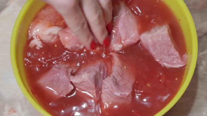 把猪肉片蘸上番茄酱腌一下。