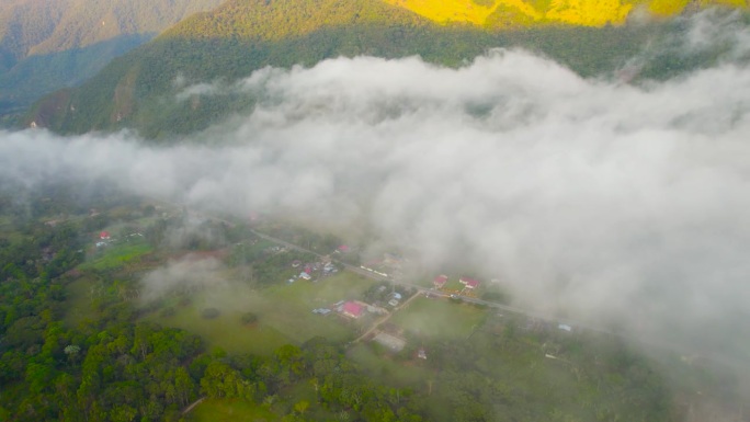 从无人机高角度拍摄的秘鲁奥克斯帕帕村的早晨。一个180度的旋转镜头显示了笼罩在云层中的村庄，房屋，郁