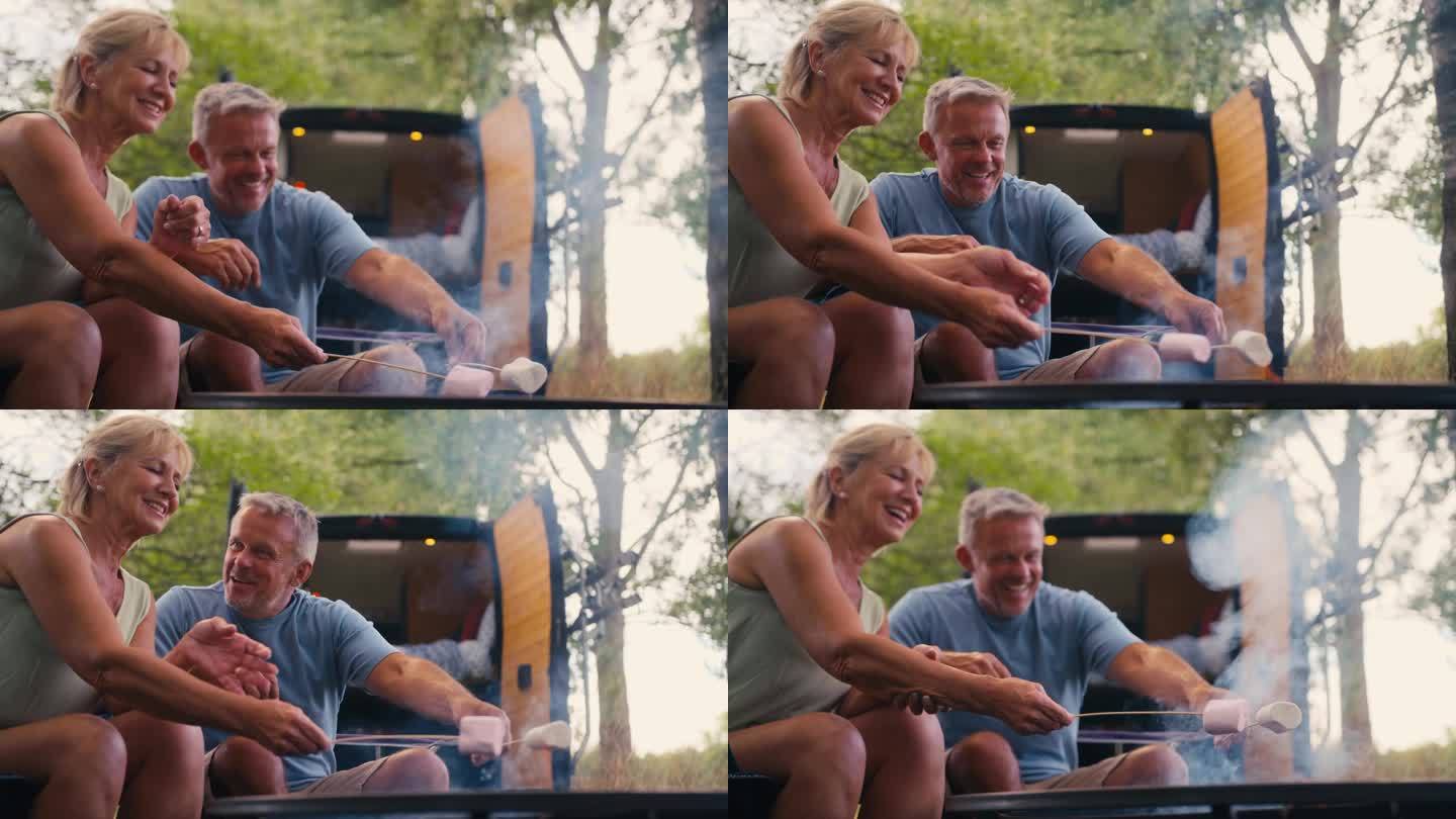 在乡村露营的老年夫妇在户外用火烤棉花糖