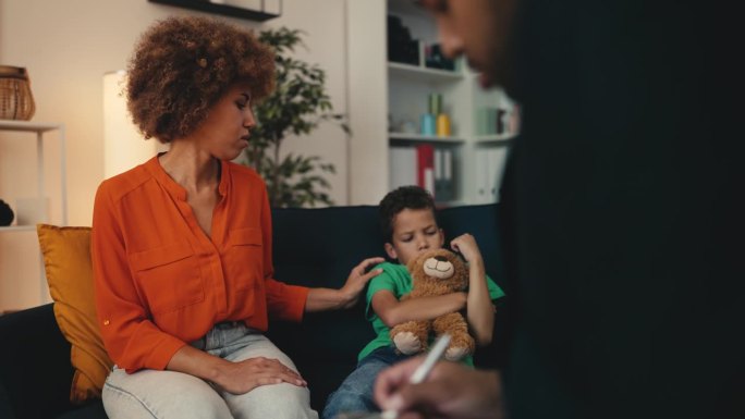 儿童治疗师与男孩和妈妈交谈，帮助他们应对情绪困扰