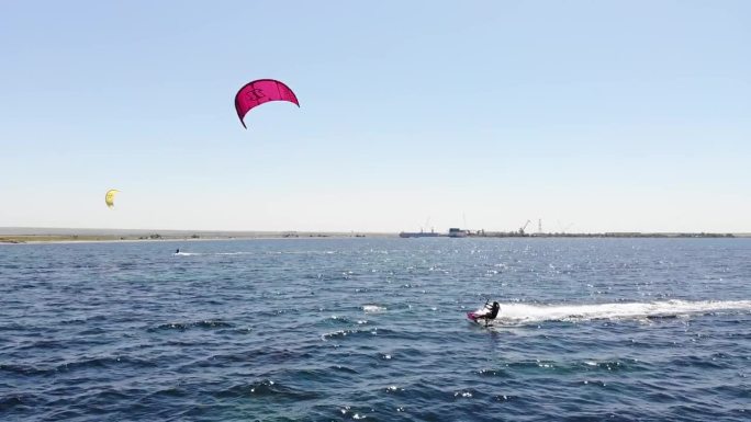 鸟瞰图，一个年轻的白人女运动员在一个阳光明媚的日子里在开阔的大海上巡航她的风筝冲浪
