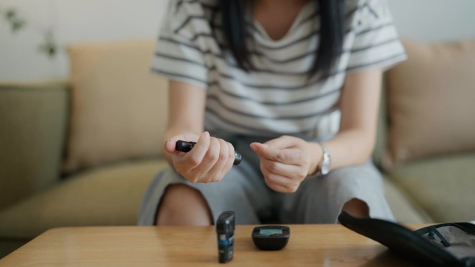 亚洲孕妇在家用血糖仪检查和测量血糖水平以控制糖尿病。
