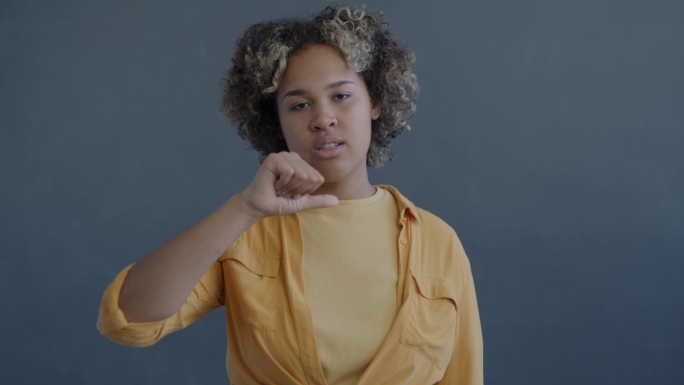 一个年轻的非裔美国妇女的慢动作肖像，先是竖起大拇指，然后又变成了向下的手势