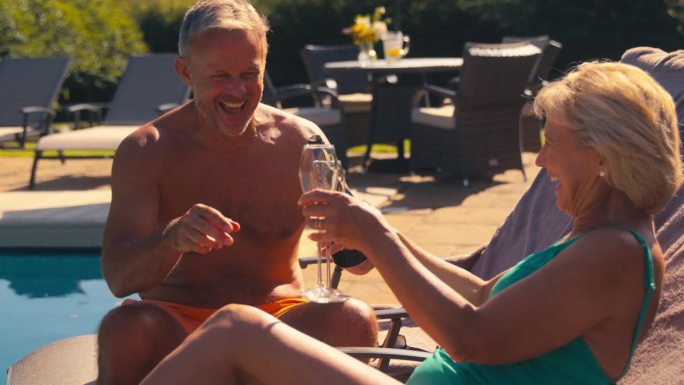 穿着泳衣度假的老夫妇在酒店游泳池开香槟