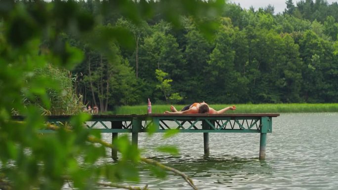在湖边运动的女人。累了，在水边的木码头上休息