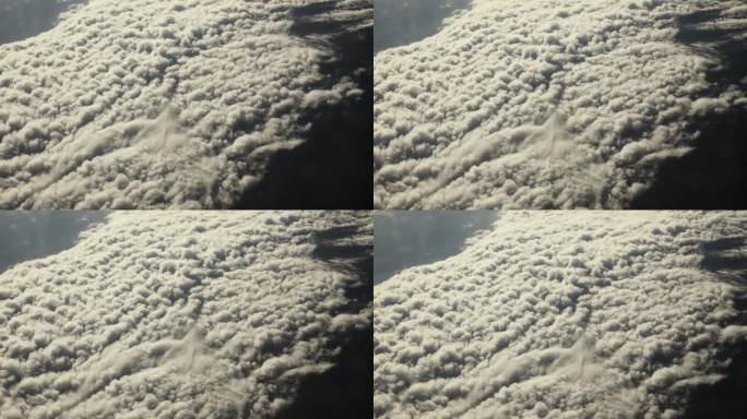 从飞机窗口鸟瞰地球。从在地球上空飞行的飞机上俯瞰大西洋上空的浮云，阳光照在地球上，呈现出电影般的慢动