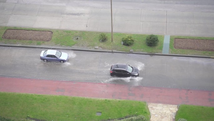 两辆车开在被水淹没的道路上，手持式跟踪