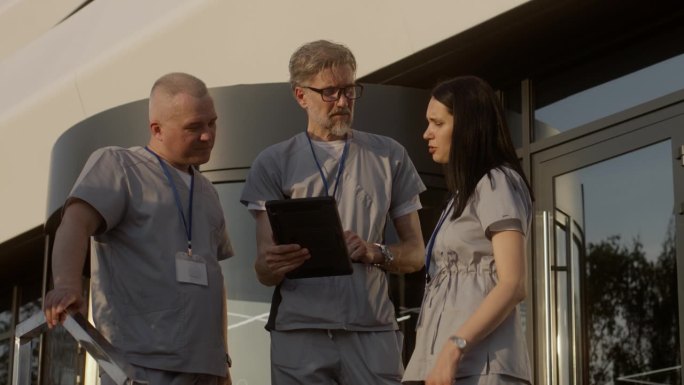 医务人员站在医院门口，使用数码平板电脑