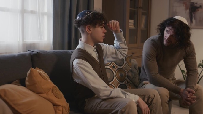 不快乐的犹太男孩在基帕和哥哥在家庭聚会上谈话