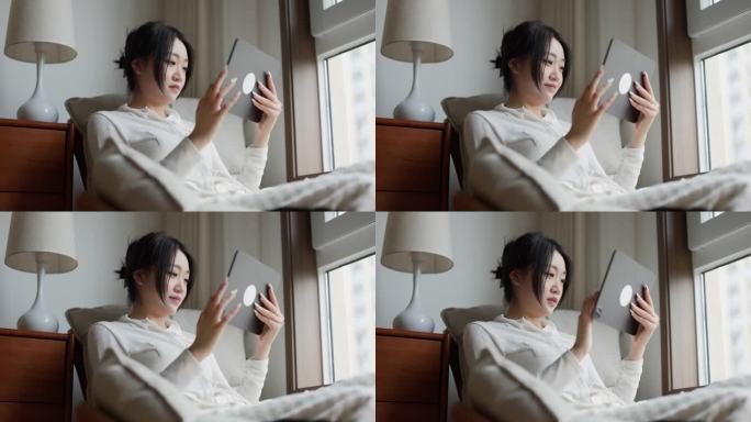 年轻的亚洲女性在家里使用数字平板电脑购物