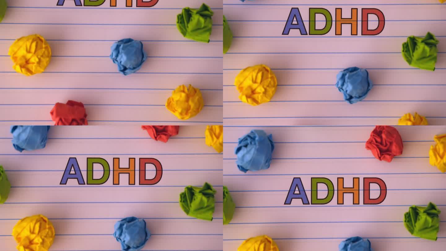 缩写ADHD在笔记本纸上，周围有一些彩色的皱巴巴的纸球