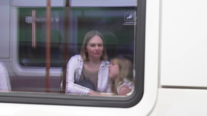地铁车窗上的倒影。妈妈和女儿在火车上。