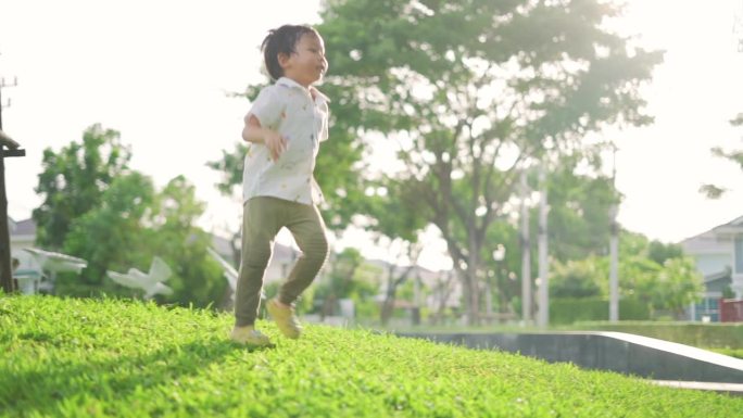 日落时分，亚洲小男孩在公园村里奔跑玩耍。