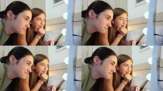 两个十几岁的朋友一起化妆，看着家里的镜子。