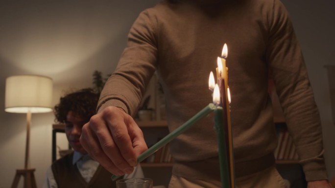 一个无法辨认的犹太男子在Hanukkiah上点燃蜡烛