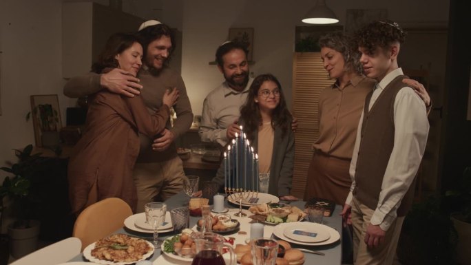 快乐的犹太六口之家在哈努克节看着燃烧的蜡烛