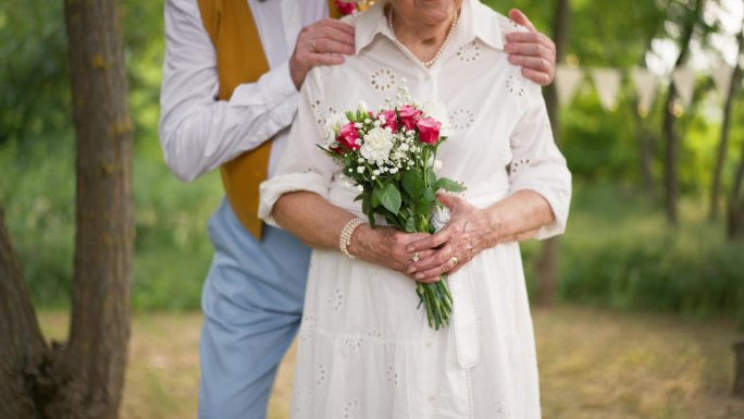婚礼中，手拿结婚花束和结婚戒指的老人。