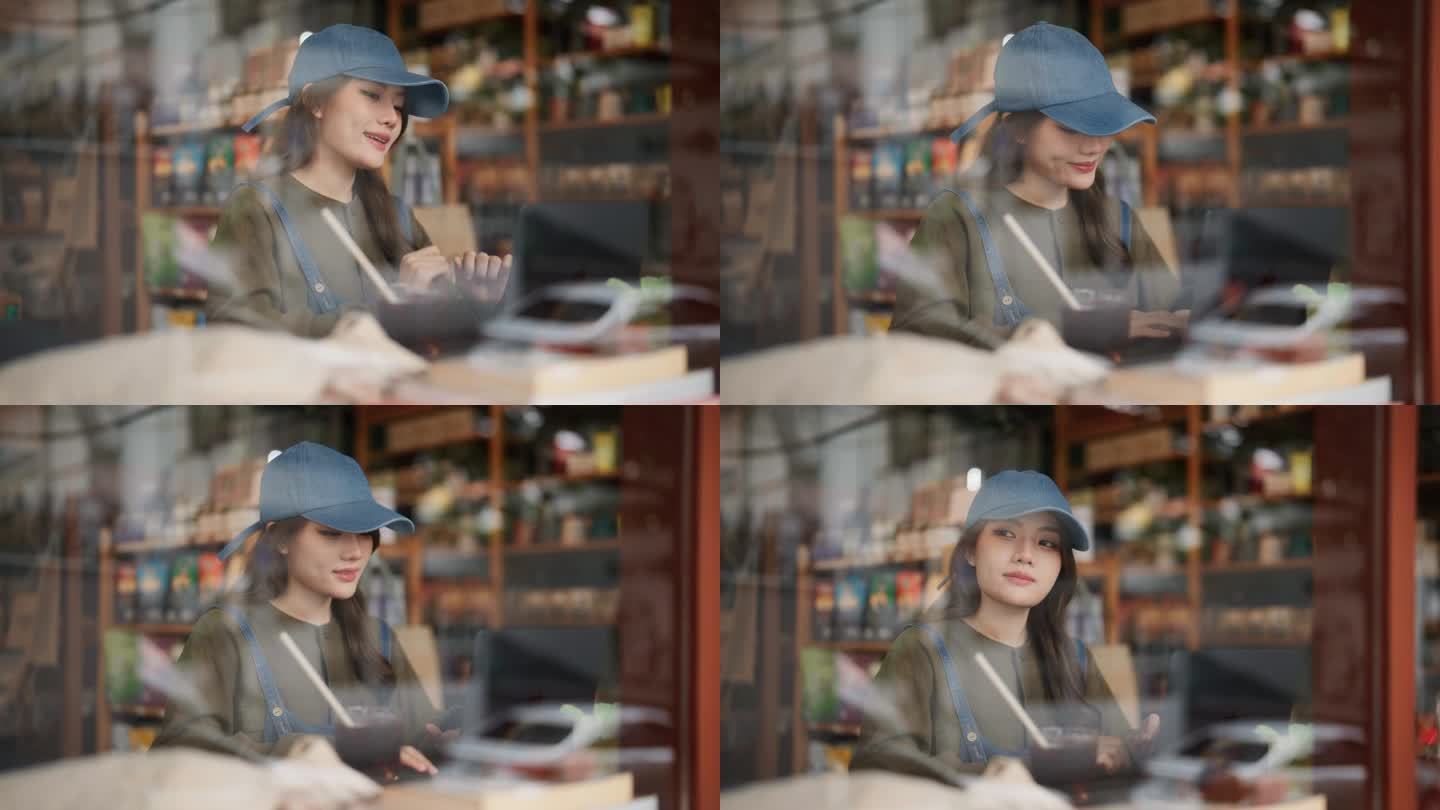 快乐的亚洲妇女坐在笔记本电脑享受网上聊天和工作在咖啡馆。