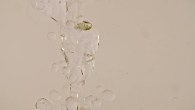 缓慢移动的油，气泡在水中上升的白色背景。带有气泡的透明化妆品凝胶液。微距镜头。