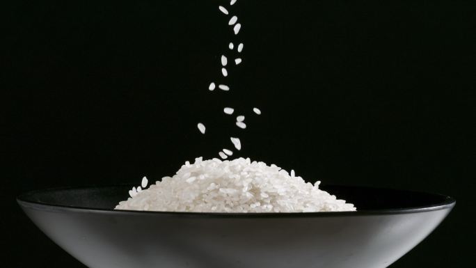 大米洒落到黑碗中 大米洒落到米堆