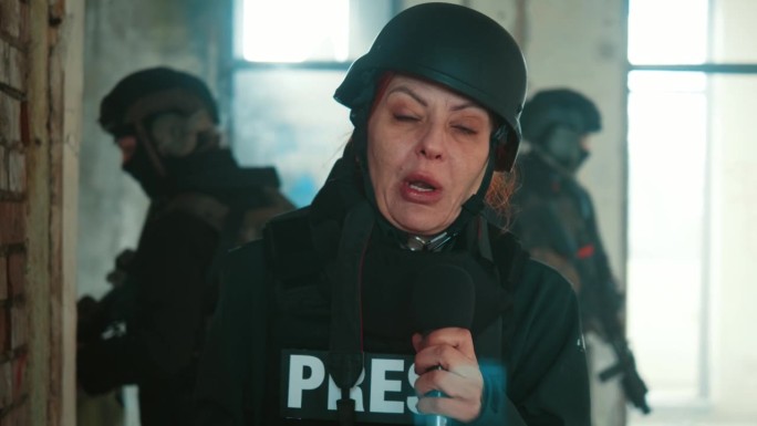 惊恐的女战地记者穿着防护背心和头盔在战区现场报道。摄像机视角，战区现场报道