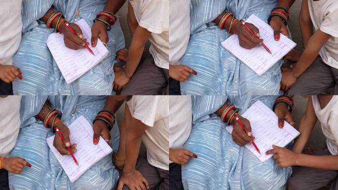 一位印度母亲带着儿子和女儿正在学习写字。成年妇女教孩子认字母。从事创造性活动的家庭
