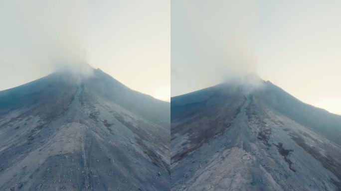 垂直视频。山顶烟雾火山口活跃喷发火山与岩石斜坡