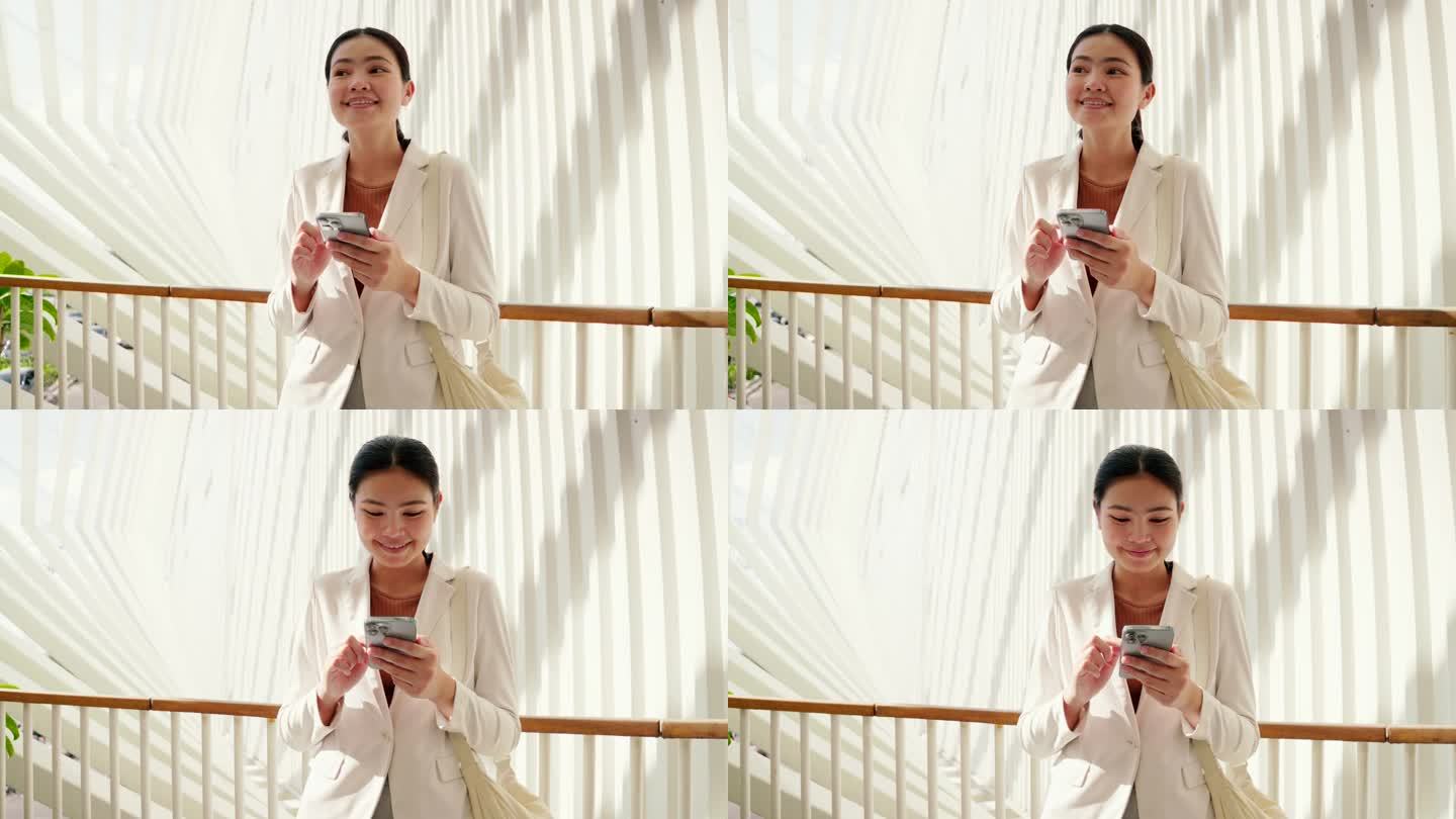一位身穿白色西装的亚洲女商人用电话与客户沟通。位于办公室花园区域